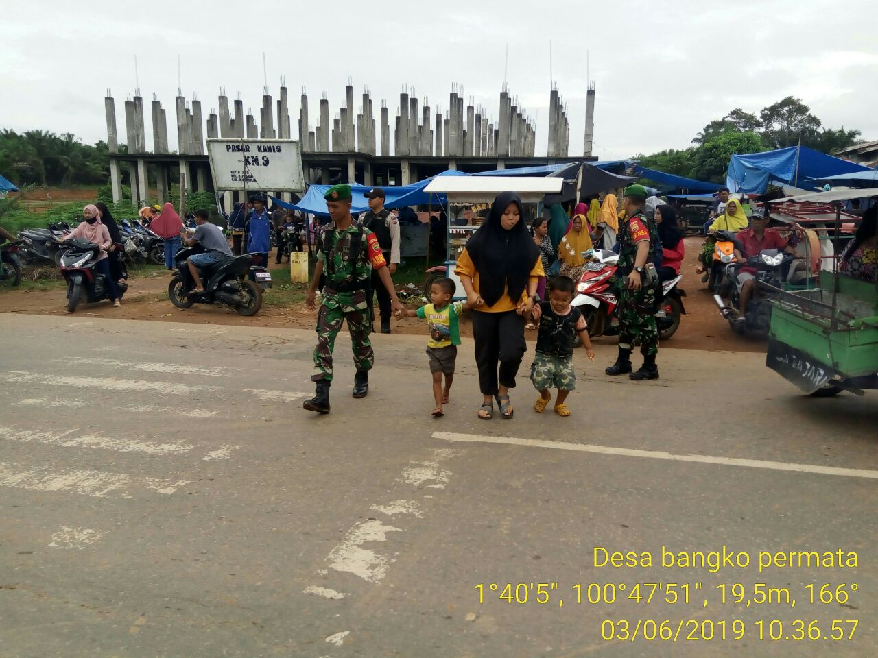 Jalan Padat Pemudik, Babinsa Koramil 05/RM Bantu Seberangkan Masyarakat Berbelanja di Pasar